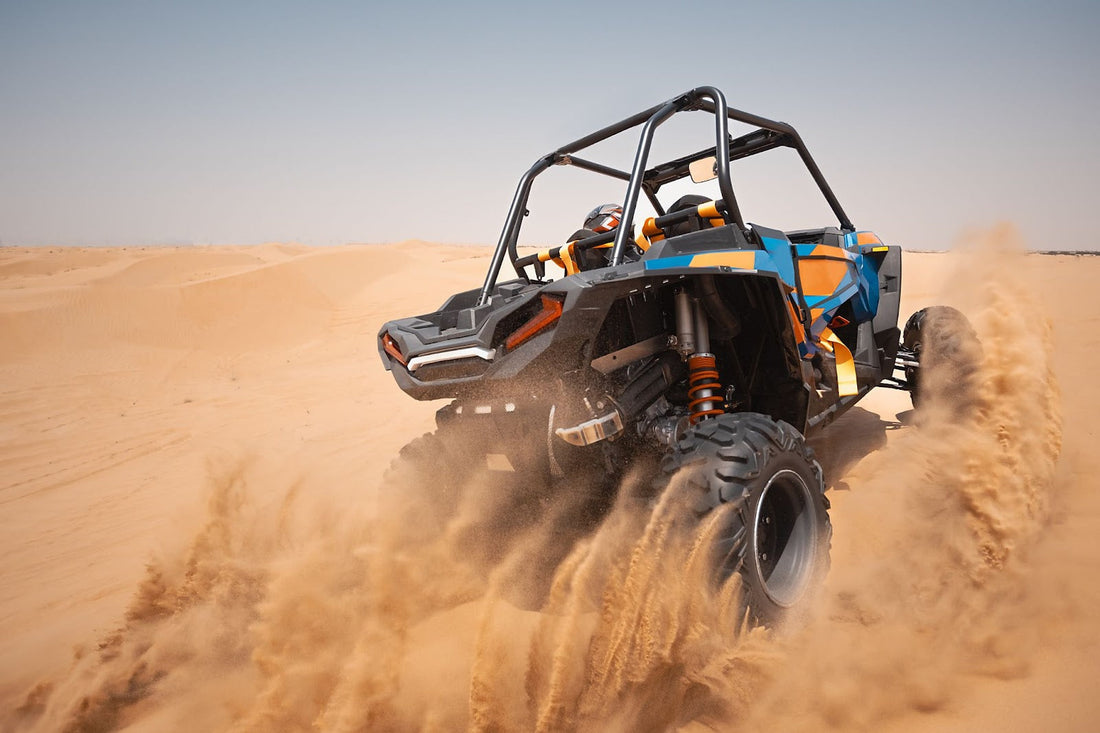 Off-road vehicle speeding through desert dunes, kicking up clouds of sand.