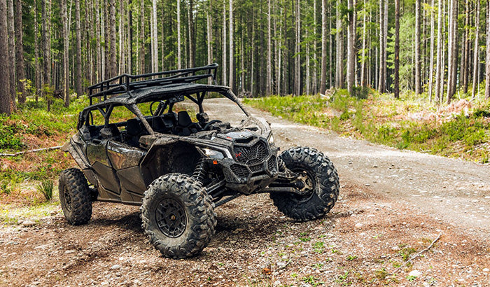 Can-Am Maverick X3, a utility task vehicle, driving on a dirt road in the woods, promoting UTV and road safety