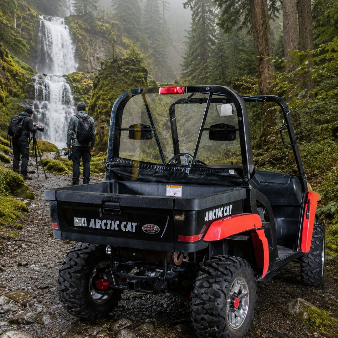 Red Arctic Cat Prowler with back windshield on a rocky trail beside a waterfall