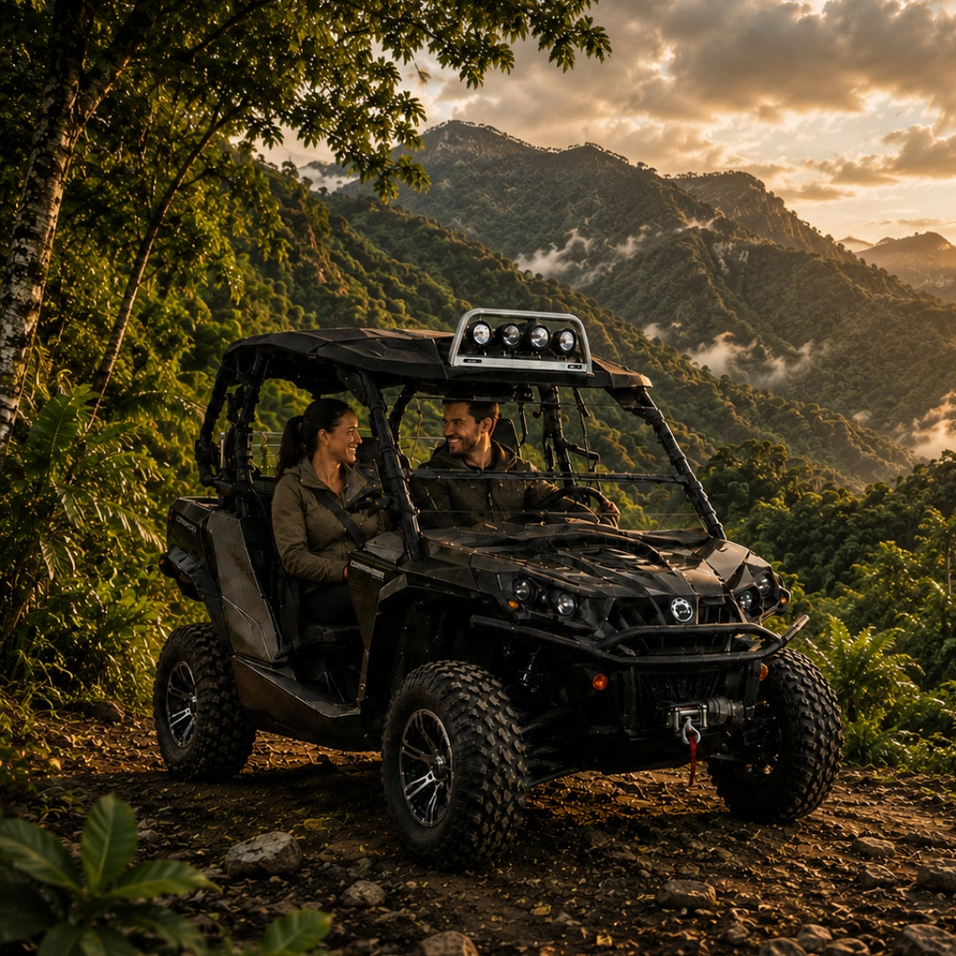 Two riders in a camo Can-Am Commander with hard top and tilting windshield in the full upright position on a mountain trail at sunset. gallery-1
