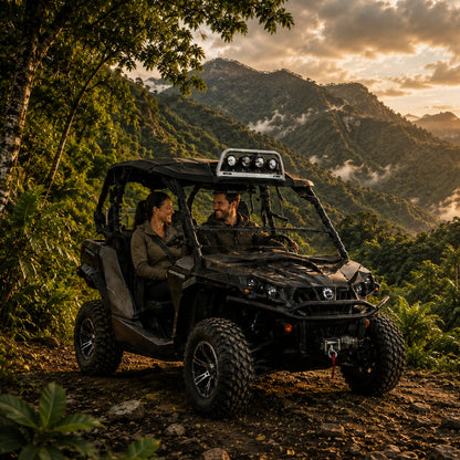 Two riders in a camo Can-Am Commander with hard top and tilting windshield in the full upright position on a mountain trail at sunset. gallery-1