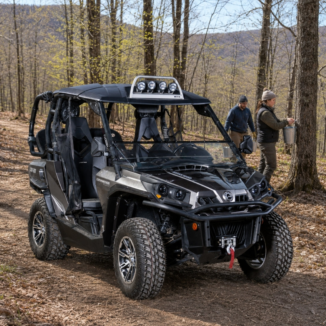 Camo Can-Am Commander with hard top and tilting windshield tilted open on a wooded trail with people alongside. gallery-1