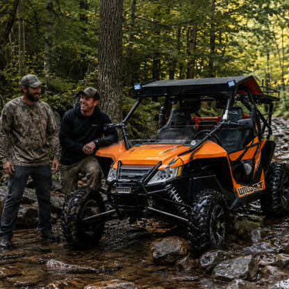 2012-2018 Arctic Cat Wildcat with a TerraRider half front windshield, parked on a wooded trail with riders