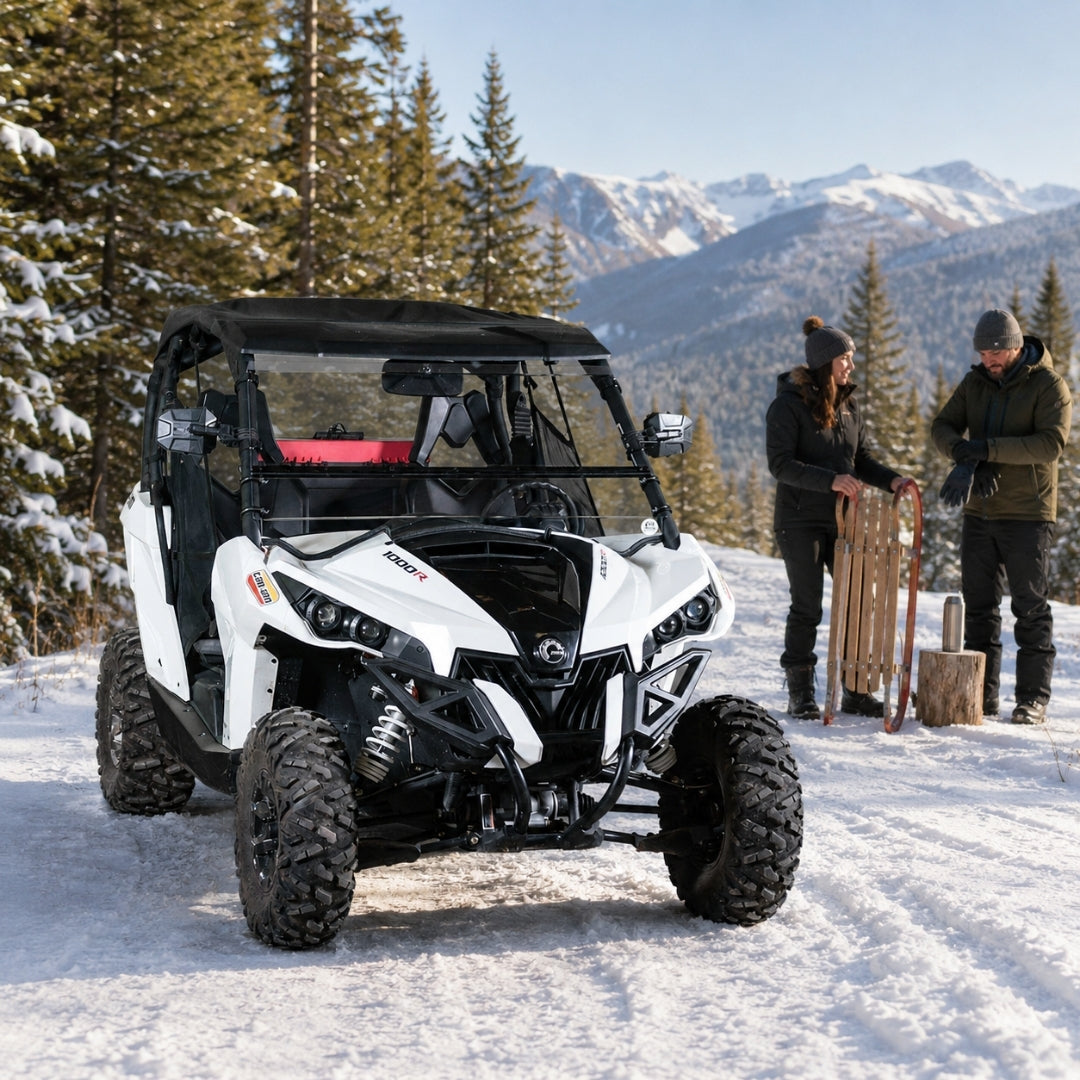 Two riders standing beside a Maverick with tilting windshield on a snow-packed mountain pullout