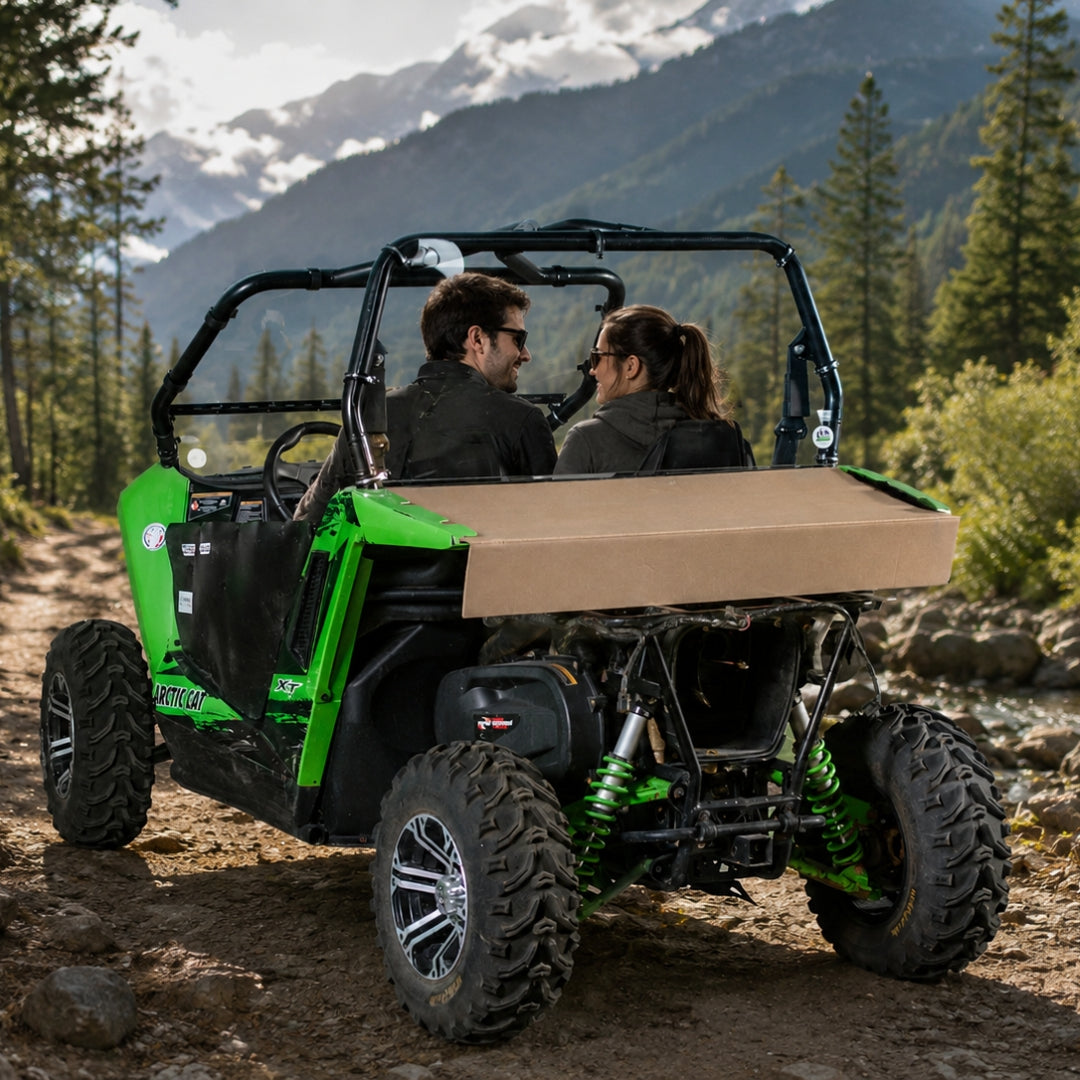 Two riders in a green Arctic Cat Wildcat Trail with back windshield on a mountain trail