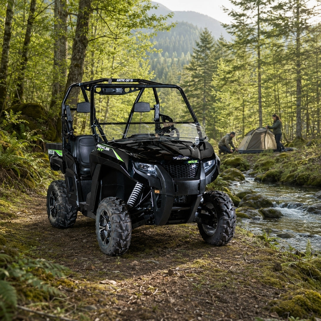 Black Arctic Cat Prowler with tilting windshield on a forest trail beside a creek