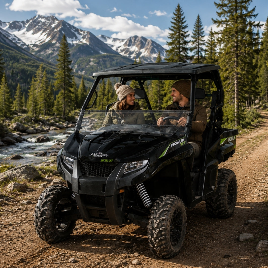 Black Arctic Cat Prowler with tilting windshield on a mountain trail with snowy peaks behind