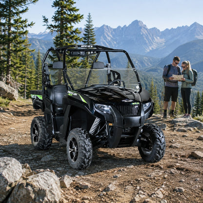 Two people beside a black Arctic Cat Prowler with half windshield on a rocky mountain trail