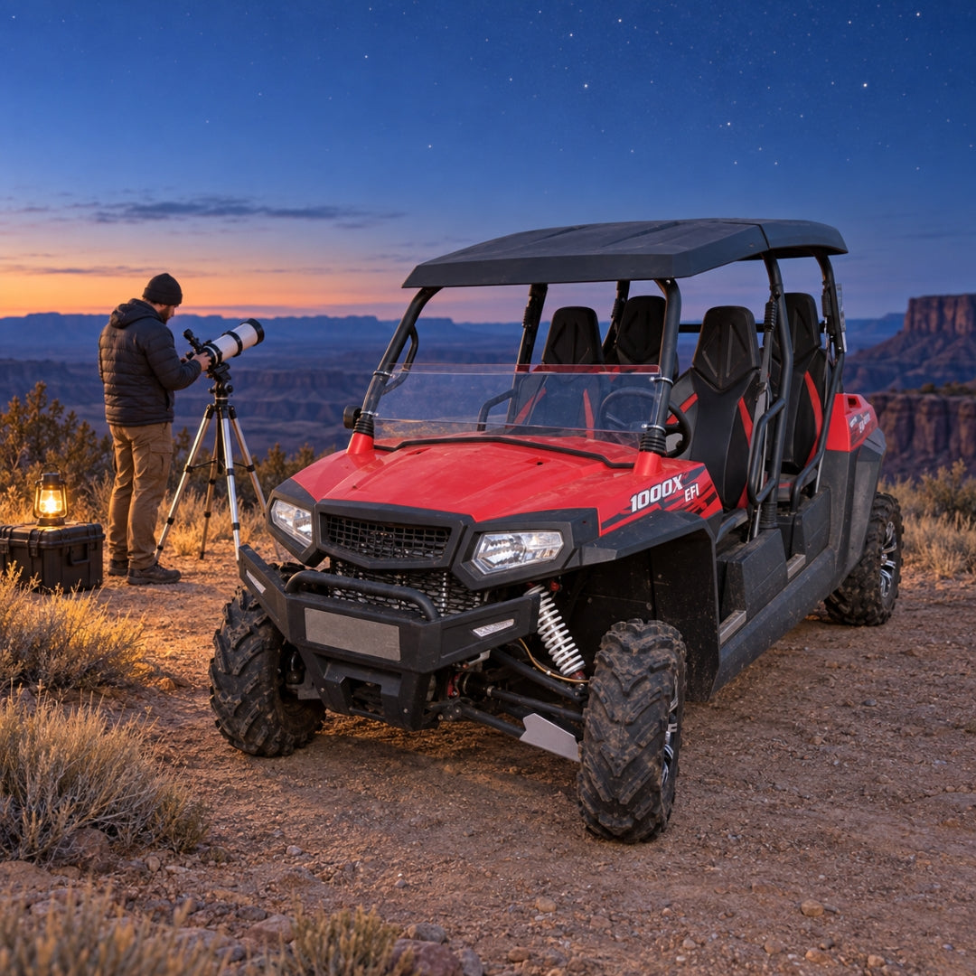 Photographer at a tripod beside a red four-door Spire 1000 on a desert overlook at dusk