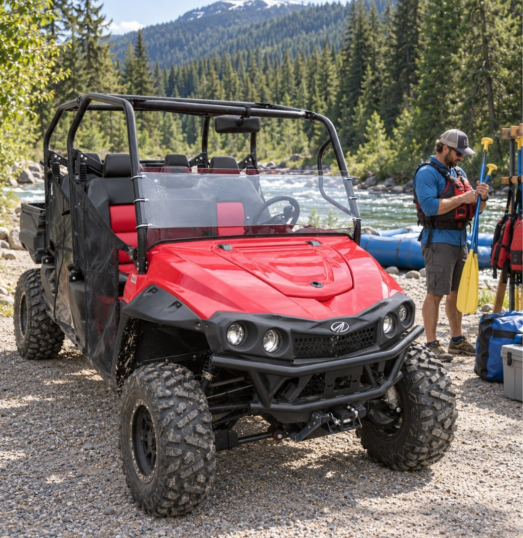 Red Mahindra mPACT XTV with half windshield at a lakeside gravel launch, owner unloading gear