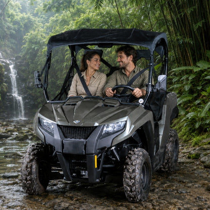 Two riders in a gray Arctic Cat Prowler 500 with full windshield beside a waterfall