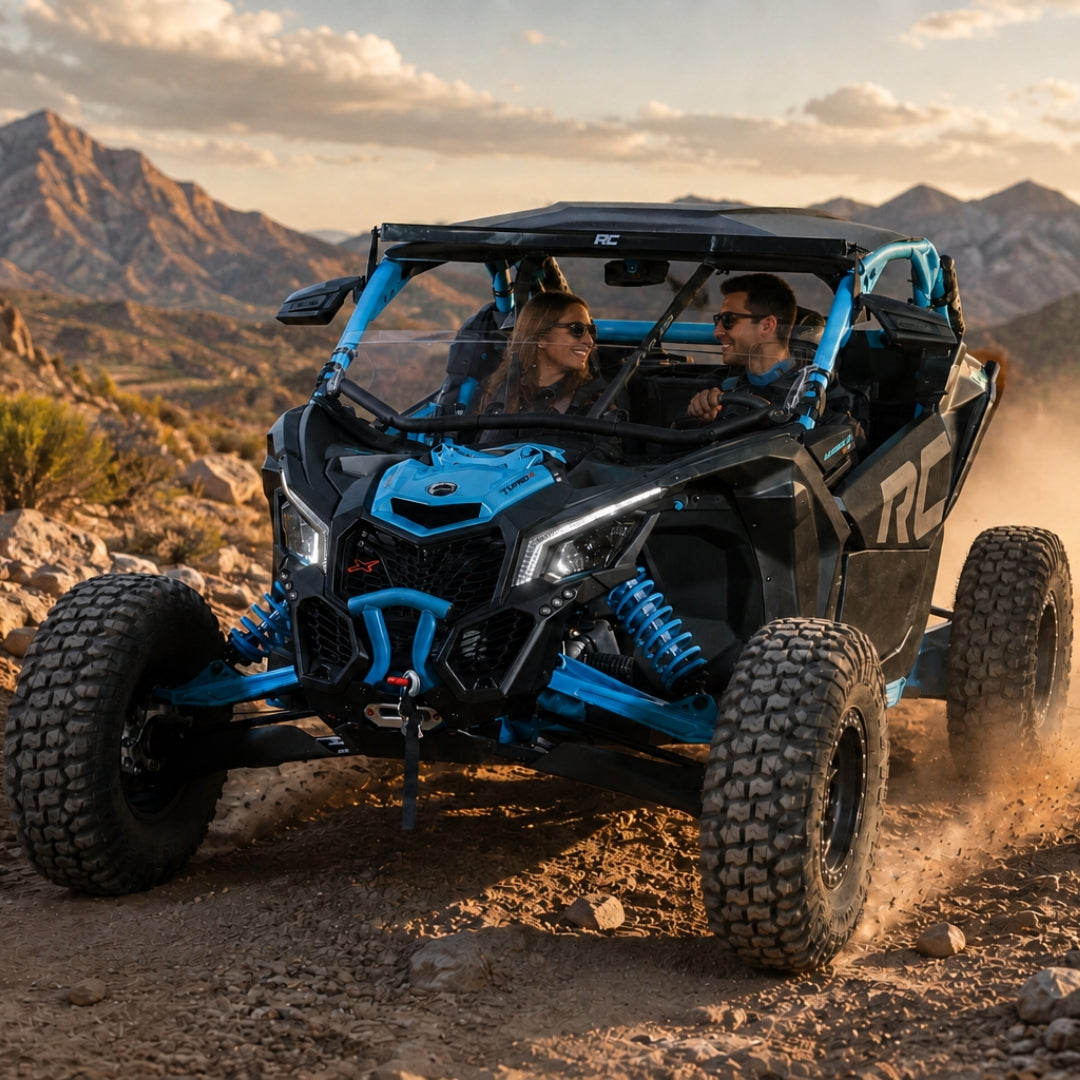 Riders in a blue Maverick X3 with half windshield on a desert ridge at sunset. gallery-1