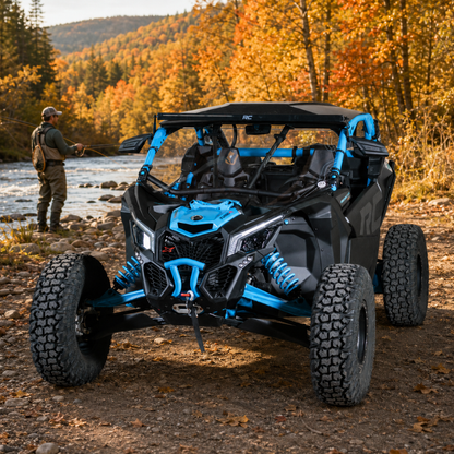 Blue Maverick X3 with full windshield beside a river in autumn, owner standing at the front. gallery-1