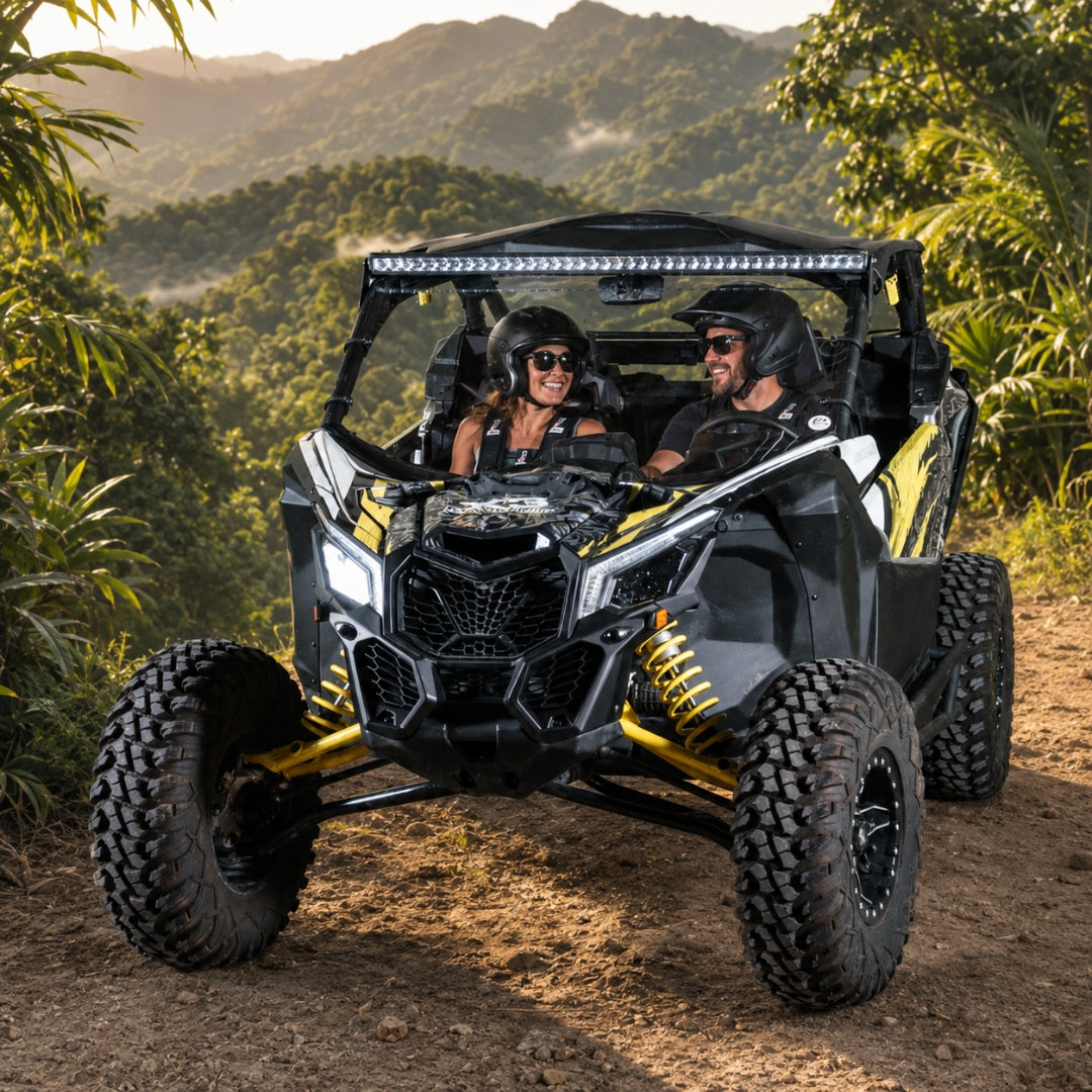 Black and yellow Maverick X3 with full windshield on a grassy mountain track, riders aboard. gallery-1