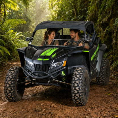 Two riders in a black Arctic Cat Wildcat XX with half windshield on a jungle trail