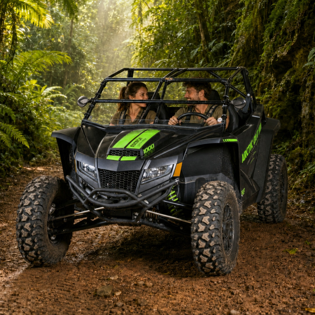 Two riders in a black Arctic Cat Wildcat XX with tilting windshield and no roof on a jungle trail