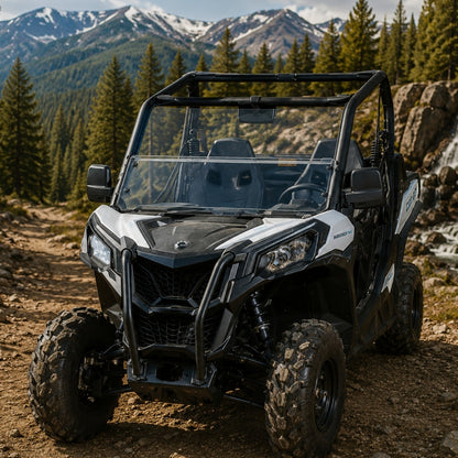 Black and white Maverick Trail with half windshield parked on a forest road below jagged peaks
