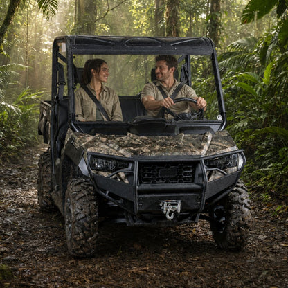 Two riders in a camo Arctic Cat Prowler Pro with full windshield on a wooded trail
