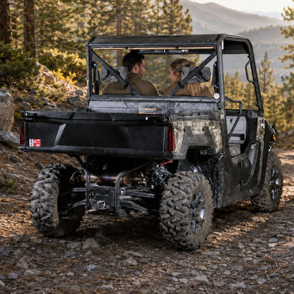 Rear view of a camo Arctic Cat Prowler Pro with back windshield on a fall wooded trail