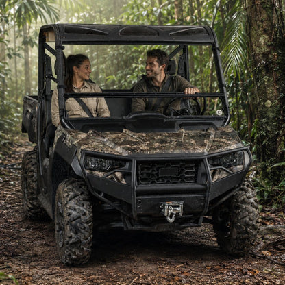 Two riders in a camo Arctic Cat Prowler Pro with tilting windshield on a wooded trail. gallery-1