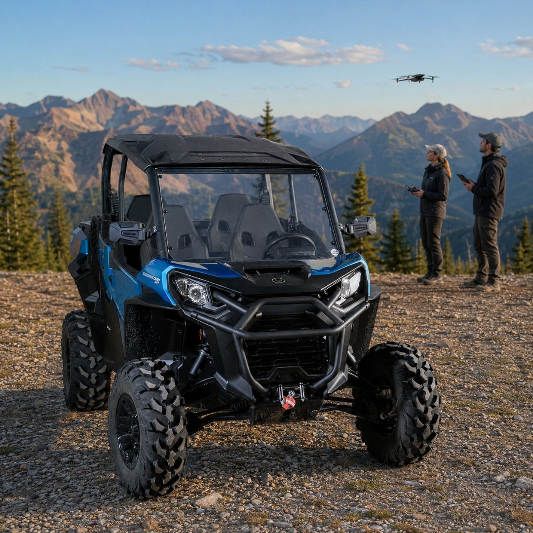 Blue Can-Am Commander with full windshield on a mountain trail with people alongside