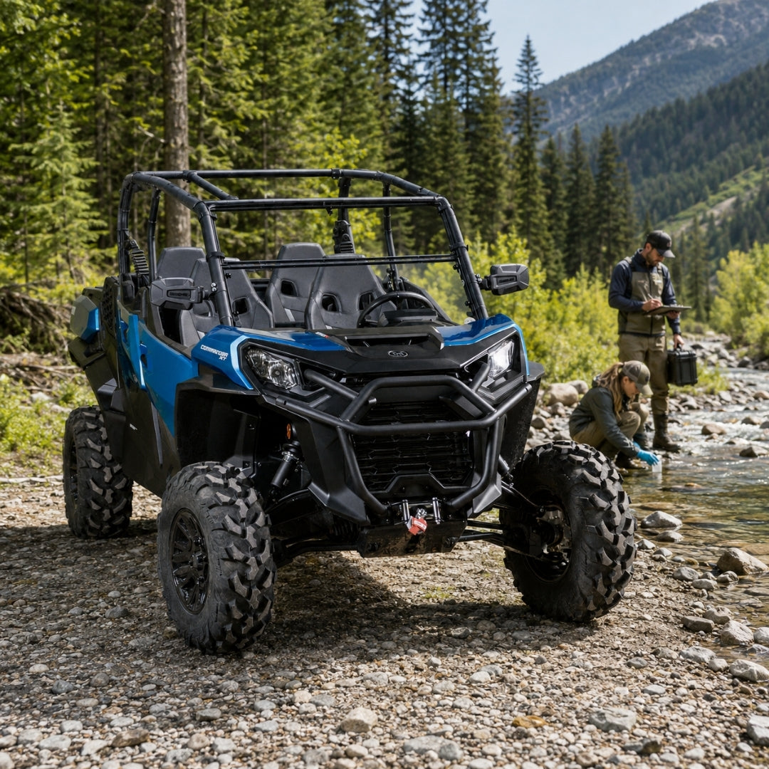 Blue Can-Am Commander with tilting windshield on a forest trail with a person alongside. gallery-2